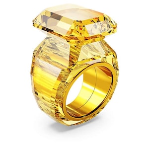 May include: A large, faceted yellow crystal ring with a gold band. The ring features a prominent, rectangular-cut crystal set atop a faceted base, creating a striking, eye-catching design. The ring's design is modern and bold, suitable for a statement piece.