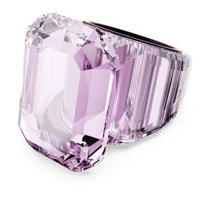May include: A large, faceted, light purple ring with a rectangular gemstone design. The ring has a clear, crystalline appearance, with multiple facets catching the light. The band is a darker purple color.