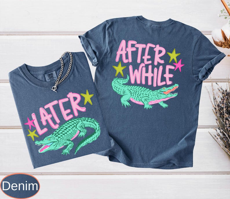 Puede incluir: Dos camisetas de color denim con dise&ntilde;os gr&aacute;ficos. Una camiseta presenta el texto "LATER" con una estrella rosa y un caim&aacute;n verde. La otra camiseta tiene "AFTER WHILE" con un caim&aacute;n verde y estrellas rosas y amarillas.