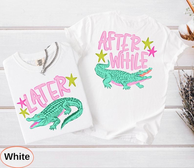 Puede incluir: Dos camisetas blancas con dise&ntilde;os a juego. Cada camiseta presenta una ilustraci&oacute;n de un caim&aacute;n verde y las frases "LATER" y "AFTER WHILE" en texto rosa con acentos de estrellas amarillas y rosas. Una cadena de plata est&aacute; en una camiseta.