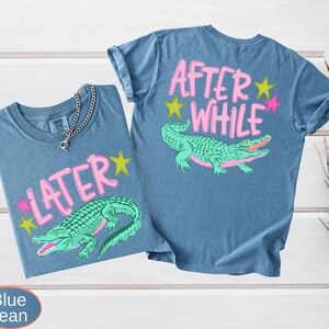 Puede incluir: Dos camisetas azul vaquero con un gr&aacute;fico de un caim&aacute;n verde y el texto "LATER" y "AFTER WHILE" en rosa. El caim&aacute;n tiene la boca roja y est&aacute; rodeado de estrellas rosas y amarillas. Una cadena de plata est&aacute; en una camiseta.