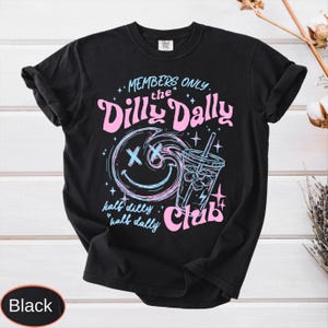 May include: Black t-shirt with a graphic design featuring the text "MEMBERS ONLY the Dilly Dally Club". The design includes a smiley face, a beverage, and stars in pink and blue.