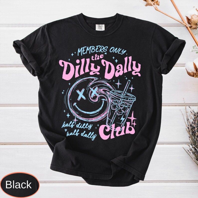 May include: Black t-shirt with a graphic design featuring the text "MEMBERS ONLY the Dilly Dally Club". The design includes a smiley face, a beverage, and stars in pink and blue.
