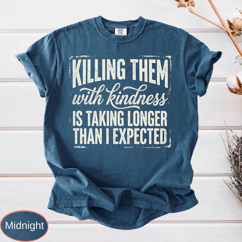 Op de afbeelding: Een nachtblauw t-shirt met korte mouwen en de witte, verweerde tekst "KILLING THEM with kindness IS TAKING LONGER THAN I EXPECTED" in een combinatie van blokletters en cursief lettertype op het midden van de borst.