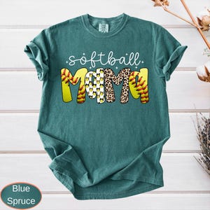 A vintage wash garment showing the text softball in cursive over the word MAMA. The thick letters showcase different designs like sports ball stitching, spotted animal print, and repeated bows, complete with tiny decorative sparkles.