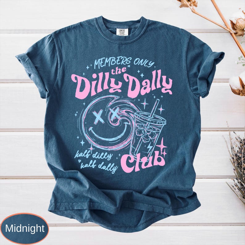 May include: Midnight blue t-shirt with a graphic design. The design features the text "MEMBERS ONLY the Dilly Dally Club" in pink, along with a smiley face and a drink. The words "half dilly, half dally" are also included.