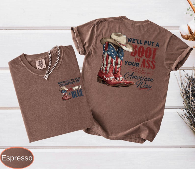 May include: Two espresso-colored t-shirts. One shirt features a small graphic of a cowboy boot with red, white, and blue colors and the text "Brought to you courtesy of Red, White & Blue." The other shirt has a larger graphic of a cowboy boot and hat with the text "We'll put a boot in your ass the American way."