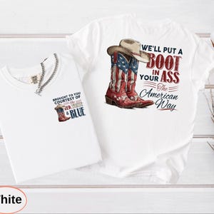 May include: Two white t-shirts. One features a graphic of a cowboy boot with the American flag design and a cowboy hat, with the text "WE'LL PUT A BOOT IN YOUR ASS The American Way." The other shirt has a smaller boot graphic and the text "BROUGHT TO YOU COURTESY OF THE RED, WHITE & BLUE."