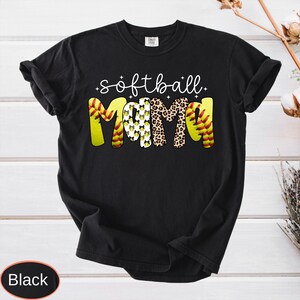 May include: Black t-shirt with the words "softball mom" in white script. The word "MOM" is in yellow, leopard print, and softball design. The shirt is a casual style.