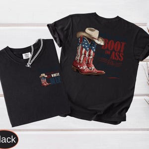 May include: Two black t-shirts. One features a graphic of red, white, and blue cowboy boots with a hat and the text "Boot in Ass". The other shirt has a small graphic of a cowboy boot and the words "Red White Blue".