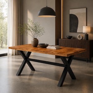 May include: A rectangular wooden dining table with a natural finish and black metal cross-shaped legs. The table is set with a vase, bowl, and books. The room has a modern, minimalist design.