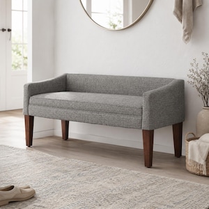 May include: A gray upholstered bench with a curved backrest and arms, featuring a textured fabric finish. The bench is supported by four straight, dark brown wooden legs. The design includes a padded seat and a continuous backrest structure.