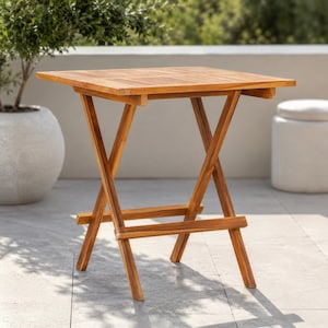May include: A square, wooden folding table with a natural finish. The table has a slatted top and an X-shaped leg design. The table is approximately 24 inches tall and 24 inches wide, ideal for outdoor use.