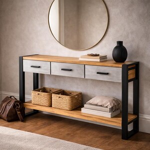 May include: A wooden console table with three gray drawers and a lower shelf. The table has black metal legs and a natural wood top. Two woven baskets and a leather bag are on the lower shelf. A round mirror hangs above the table.