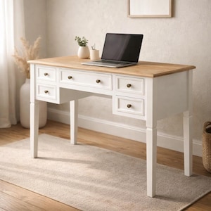 May include: A white wooden desk with a light brown tabletop. The desk has six drawers with brass knobs and four legs. A laptop, a small vase with plants, and a pen holder are on the desk.