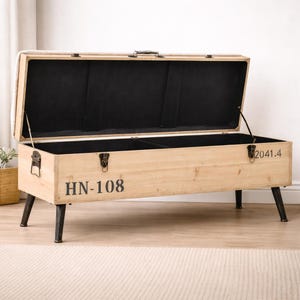 May include: A light-colored wooden storage bench with a hinged lid, open to reveal a black interior. The bench has black metal legs and hardware, with the text "HN-108" printed on the front. The bench is 50 inches long.