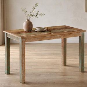 May include: A rectangular wooden dining table with a distressed finish. The tabletop features a mix of brown, green, and blue hues. The legs are painted in a distressed green color. A vase, bowl, and glass are on the table.