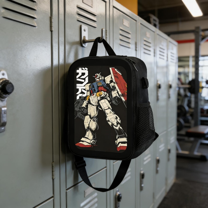 May include: Black lunch bag with a graphic of a Gundam robot in red, white, blue, and yellow. The bag has a black shoulder strap and a side mesh pocket. The Japanese text "ガンダム" is printed on the left side of the robot.