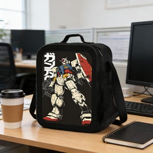 May include: Black lunch bag featuring a colorful illustration of a robot with a red, white, blue, and yellow color scheme. The robot is set against a black background with Japanese text. The bag has a handle, shoulder strap, and a side pocket.
