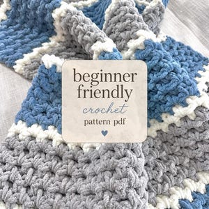 May include: A chunky crochet blanket featuring horizontal stripes in blue, gray, and white. A square overlay in the center displays the text: beginner friendly crochet pattern pdf with a small blue heart icon at the bottom of the text block.
