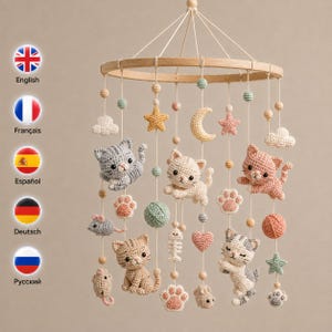 Puede incluir: Un móvil circular de madera para bebé con figuras de ganchillo que incluyen gatitos grises, blancos y rosas, ratones, ovillos de lana, espinas de pescado, corazones, estrellas, lunas, nubes y huellas de patas suspendidos de un aro de madera.