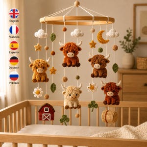 Könnte beinhalten: Ein Baby-Mobile mit einem runden Holzrahmen und hängenden Häkelelementen, darunter fünf Highland-Rinder in Braun und Creme, eine rote Scheune, ein Heuballen, weiße Wolken, eine gelbe Mondsichel, Sterne, Blumen und grüne Blätter.