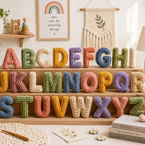 May include: A complete set of twenty-six individual letters of the alphabet, each crafted from colorful crocheted yarn. The letters are arranged in three rows on a tiered wooden display stand, featuring a variety of pastel and vibrant yarn colors.