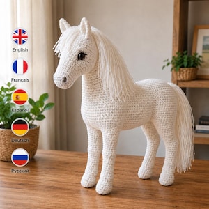 Puede incluir: Un juguete de caballo tejido a ganchillo en color blanco con un cuerpo de hilo texturizado, una larga crin fluida y una cola a juego. El caballo tiene ojos de color marrón oscuro y se sostiene sobre cuatro patas con detalles de costura en toda la figura.