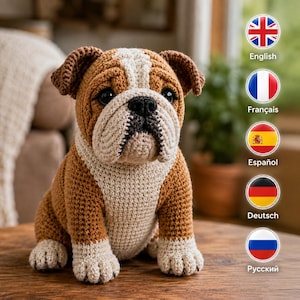 Può includere: Una statuetta di bulldog all'uncinetto con un motivo di colore marrone e bianco. L'animale di peluche ha una superficie in filato testurizzato, occhi scuri e un naso nero. È seduto in posizione eretta con le zampe anteriori rivolte in avanti.