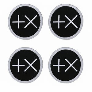 May include: Four circular patches with a black background and a white border. Each patch features a white plus sign with an X through it. The patches are arranged in a two-by-two grid.