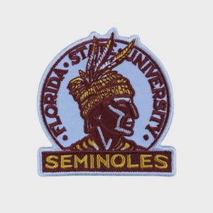 Può includere: Toppa ricamata con il logo dei Seminoles della Florida State University. La toppa ha uno sfondo azzurro con le parole "FLORIDA STATE UNIVERSITY" in un motivo circolare. Il logo dei Seminoles è un profilo di una figura nativa americana in bordeaux e oro.