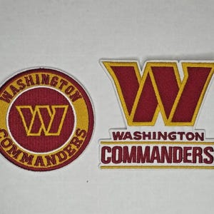 May include: Two embroidered patches featuring the Washington Commanders logo. One is circular with the team name and logo, the other is rectangular with the team name and a stylized "W" logo. Both have burgundy, gold, and white colors.
