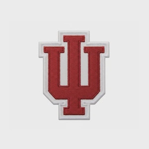 May include: Embroidered patch featuring the Indiana University logo, a stylized letter "I" with a "U" shape. The patch has a red design with a white border. The patch is likely for apparel or accessories.