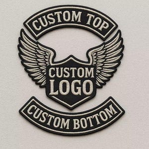 May include: A set of three black and white embroidered patches. The top patch reads "CUSTOM TOP" in white, arched text. The center patch features a shield shape with "CUSTOM LOGO" and wings. The bottom patch reads "CUSTOM BOTTOM".
