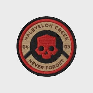May include: Embroidered patch with a circular design. The patch features a red skull emblem at the center, surrounded by the words "Malevelon Creek" and "Never Forget." The patch has a black, tan, and red color scheme.