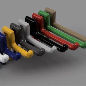 Puede incluir: Una colección de ganchos de pared coloridos en varios tonos, incluyendo blanco, azul, amarillo, gris, negro, rojo, verde y beige. Cada gancho tiene un diseño curvo para colgar objetos. Los ganchos están dispuestos en fila, mostrando su diversa paleta de colores.