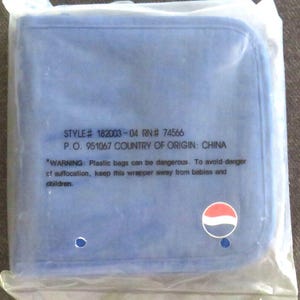 May include: A blue square item, possibly a cloth or pad, is packaged in a clear plastic bag. The bag has text that includes a style number, RN number, and the country of origin, China. A Pepsi logo is visible.