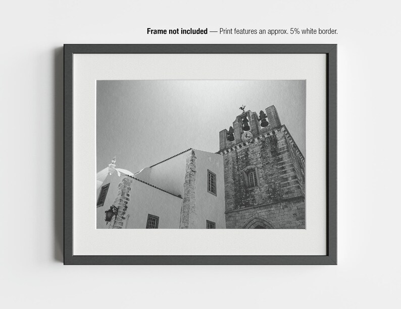May include: Black and white photograph of a church building with a bell tower. The image is framed in a black border with a white mat. The text "Frame not included - Print features an approx. 5% white border" is at the top.