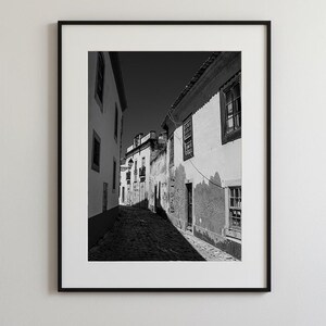 Black and white framed wall art of a narrow cobblestone street in Faro Old Town, Portugal. Rustic European architecture print.