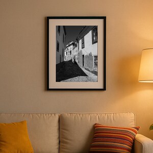 Faro Old Town street photography hanging above a beige sofa. Cozy living room wall decor with rustic black and white art.