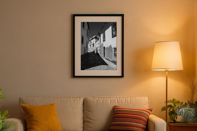 Faro Old Town street photography hanging above a beige sofa. Cozy living room wall decor with rustic black and white art.