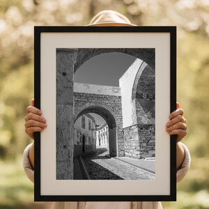 Person holding a framed print of the Faro stone archway. Demonstrates the scale of this large rustic architecture wall art, perfect for visualizing the size.