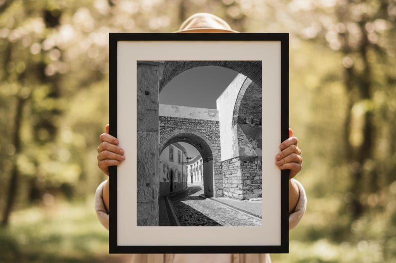 Person holding a framed print of the Faro stone archway. Demonstrates the scale of this large rustic architecture wall art, perfect for visualizing the size.