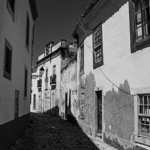 Close up detail of textured walls and cobblestones in a historic Portuguese alleyway. Vertical fine art photography print.