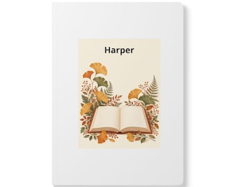 Può includere: Un taccuino bianco con un'illustrazione centrale di un libro aperto circondato da foglie di ginkgo e felci arancioni e verdi. Il nome Harper è stampato in nero sopra il libro su uno sfondo color crema.