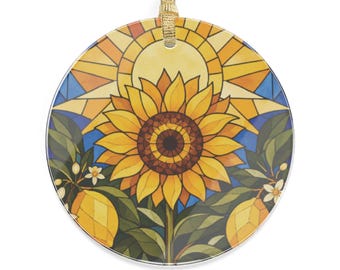Peut inclure: Une décoration suspendue circulaire présentant une illustration de style vitrail d'un grand tournesol jaune centré sous un soleil brillant. Le motif comprend des feuilles vertes, de petites fleurs blanches et deux citrons jaunes sur un fond bleu.