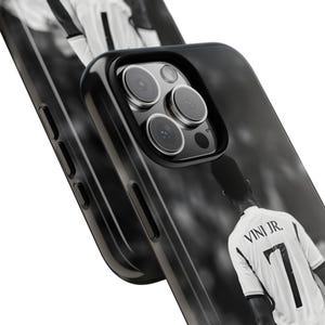May include: A black smartphone case featuring a black and white graphic of a soccer player wearing a jersey with the text VINI JR. and the number 7 on the back. The case has a cutout for a triple-lens camera system and side buttons.