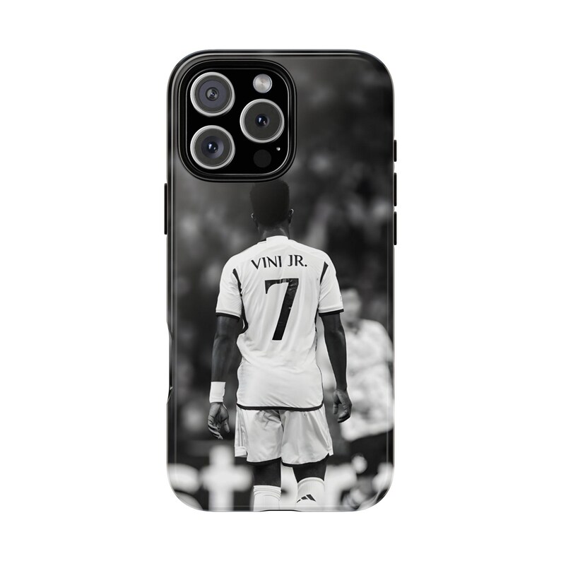 May include: A black and white smartphone case featuring a rear view of a soccer player wearing a jersey with the text VINI JR. and the number 7 on the back. The design shows the player standing on a field with a blurred stadium background.