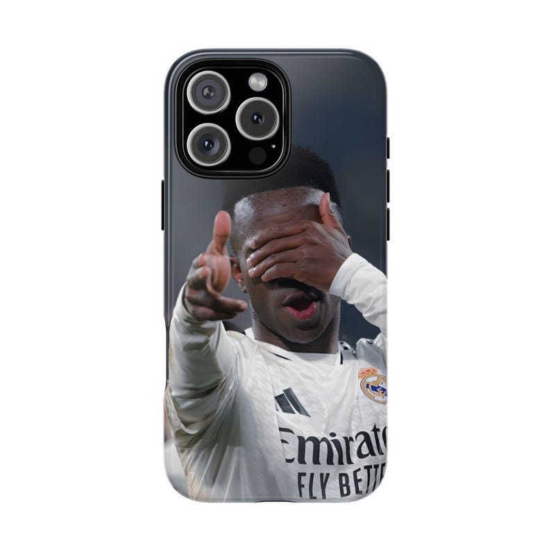 May include: A black smartphone case featuring a photographic print of a soccer player in a white jersey with the text Emirates FLY BETTER. The player is shown with one hand covering their eyes and the other hand extended forward in a gesture.