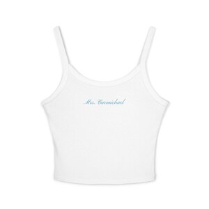 May include: White ribbed tank top with thin straps. The text "Mrs. Carmichael" is embroidered in light blue on the front. This casual top is suitable for everyday wear.